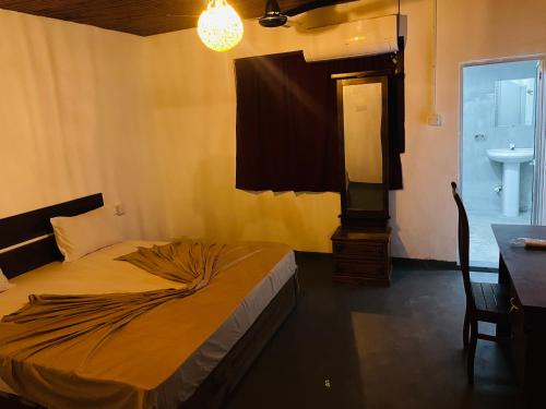 a bedroom with a bed and a sink and a table at Ryo hostel in Ahangama