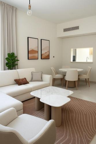 a living room with white furniture and tables at Elegant 1BR Yas Island with Theme Park Views & Exclusive Yas Park Offers in Abu Dhabi