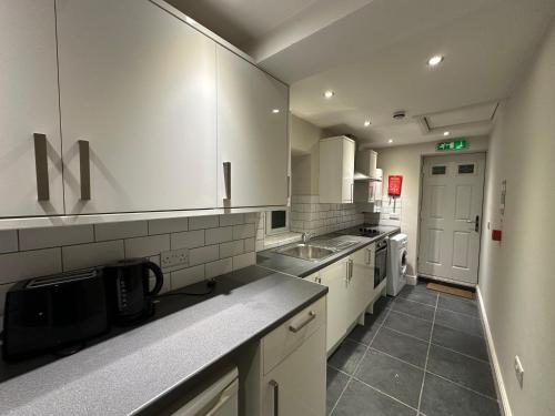 a large kitchen with white cabinets and a sink at OYO Cavendish Annexe in High Wycombe