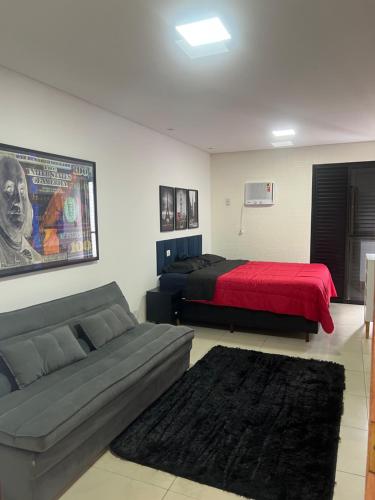 a bedroom with a bed and a couch with a red blanket at Flat Palladium in São Vicente