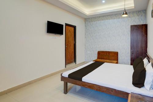 Un dormitorio con una cama y un televisor en la pared. en Hotel O NEW CLARK INN & BANQUET, en Bādshāhnagar