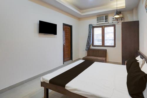 Un dormitorio con una cama y un televisor en la pared. en Hotel O NEW CLARK INN & BANQUET, en Bādshāhnagar