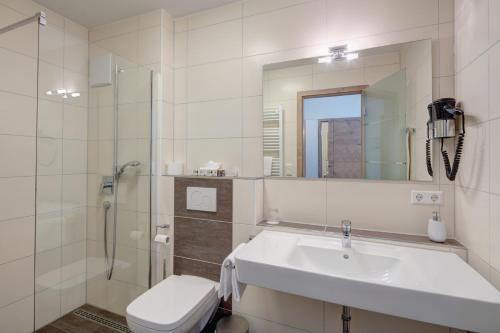 ein Badezimmer mit einem Waschbecken, einem WC und einem Spiegel in der Unterkunft Vinotel Heinz J. Schwab in Bretzfeld