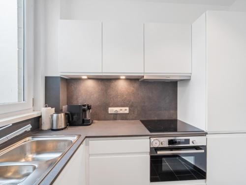 een keuken met witte kasten en een spoelbak bij Leopold - 0102 in Blankenberge