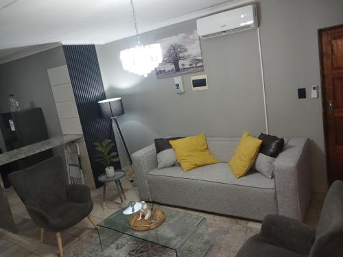 a living room with a gray couch and yellow pillows at Waterfall Deluxe in Rustenburg