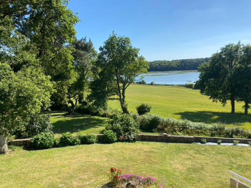 un jardin avec vue sur un champ et un lac dans l'établissement Maison sur le golfe du Morbihan vue mer, à Plougoumelen