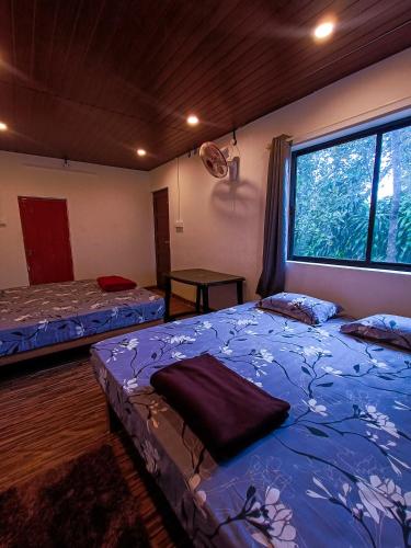 a room with two beds and a large window at Mountain Vista Vagamon in Vagamon