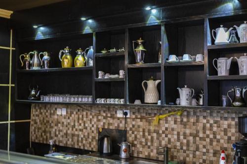 une cuisine avec des étagères remplies de vases et de pichets dans l'établissement Quiet Rooms 8, à Riyad