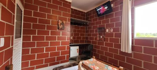 a bathroom with a red brick wall at Pousada Itatiba Holliday in Itatiba