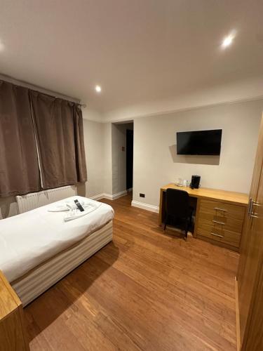 a bedroom with a bed and a desk and a television at OYO Cavendish Annexe in High Wycombe
