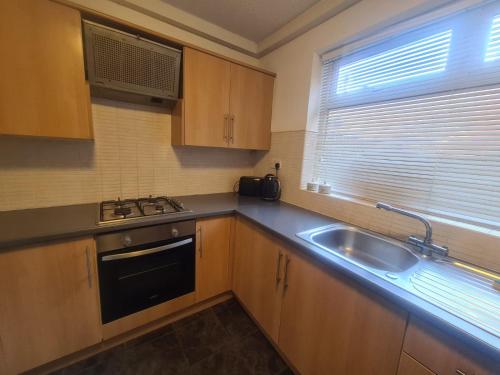 a kitchen with wooden cabinets and a sink and a window at 2 bed central apartments in South Shields