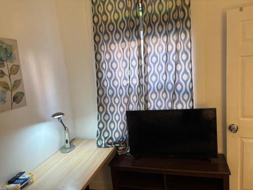 a television sitting on a wooden table next to a window at EN SUITE NEXT TO FELLS POINT in Baltimore