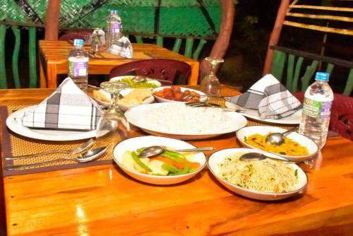 a wooden table with plates of food on it at Wild Safari River Cottage Udawalawa in Udawalawe