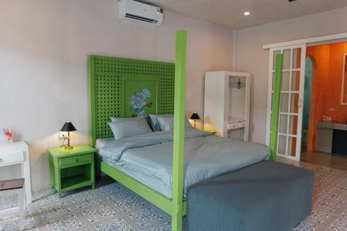 une chambre avec un lit à baldaquin vert dans une pièce dans l'établissement Watercolours, à Ko Chang