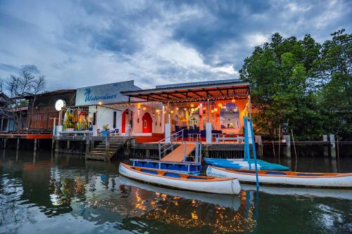 two boats are sitting in the water in front of a building at Watercolours in Ko Chang