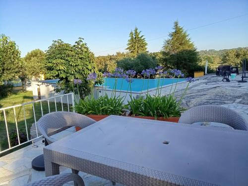 einen weißen Tisch und Stühle auf einem Balkon mit Pool in der Unterkunft Quintinha das Artes - Turismo Rural in Pinhel
