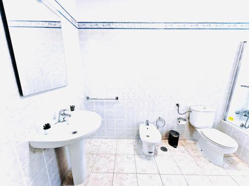 a white bathroom with a sink and a toilet at Studio com vista para Rua da Oura - Albufeira in Albufeira
