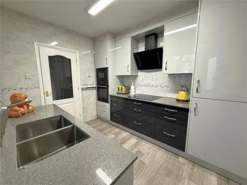 a large kitchen with a sink and a refrigerator at A beautiful stylish home in city centre in Camberley