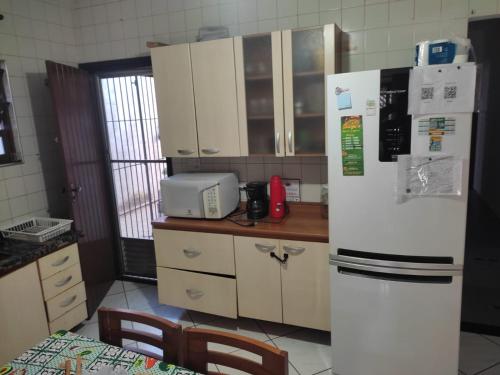 a kitchen with a white refrigerator and a microwave at Casa Tupy próxima a praia e restaurantes in Praia Grande