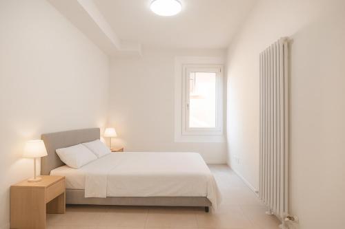 博洛尼亚Lambrusco Apartment in the heart of Bologna的一间带床和窗户的白色卧室