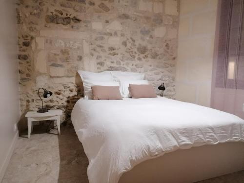 阿尔勒Extraordinaire face aux Arènes的卧室配有一张白色的大床和石墙