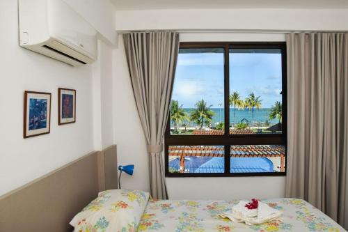 Schlafzimmer mit einem Bett und einem Fenster mit Meerblick in der Unterkunft Maui Beach Residence in Tamandaré