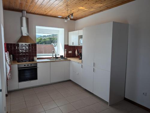 eine Küche mit weißen Schränken und einem großen Fenster in der Unterkunft Casa de São João in São João