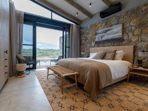 Izakithi River Villa في ماليلين: غرفة نوم بسرير كبير وجدار حجري