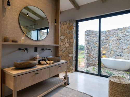 Izakithi River Villa في ماليلين: حمام مع حوض وحوض استحمام ومرآة