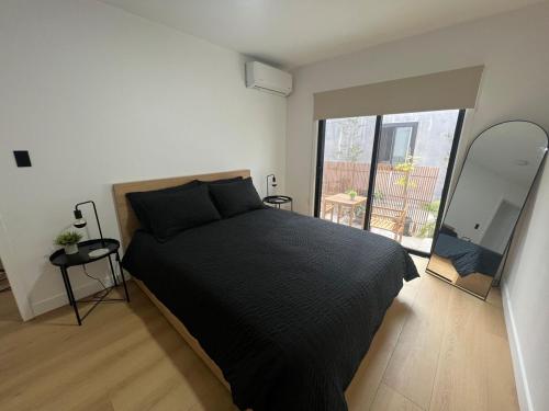 ein Schlafzimmer mit einem schwarzen Bett und einem großen Fenster in der Unterkunft East Hollywood Modern Spacious Bungalow in Los Angeles