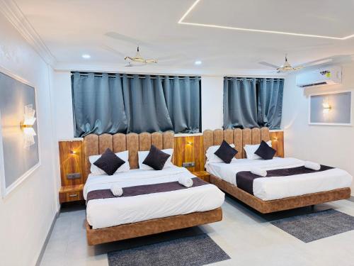 Dos camas en una habitación con cortinas azules. en Hotel JK Palace, en Ujjain