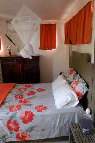 una camera da letto con un letto con fiori rossi sopra di ALAMANDA DES ILES, a Sainte-Anne