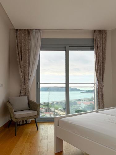 a bedroom with a bed and a chair and a large window at Seaview Apartment in Bečići