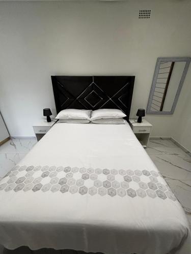 德班Rephidim Palace 02的一间卧室配有一张白色大床和黑色床头板