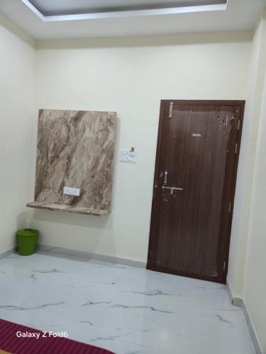 una puerta de madera en una habitación con una pintura en la pared en Shrimant Executive Lodging, en Jejūri
