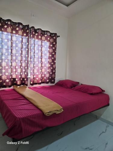 Un dormitorio con una cama con sábanas moradas y una ventana. en Shrimant Executive Lodging, en Jejūri