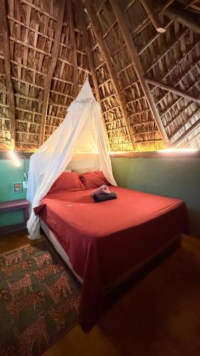 a bedroom with a bed in a thatched roof at El Chiringuito, Mermejita in Mazunte