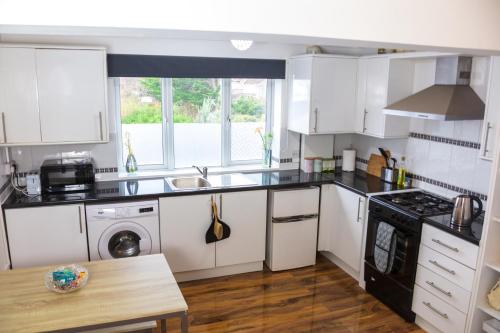 a kitchen with white cabinets and a stove top oven at Freshly Renovated Apartment on High Street in Saltdean