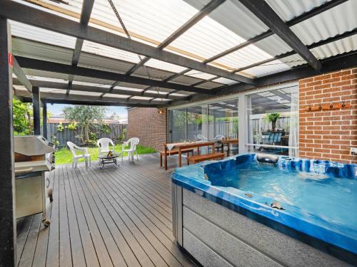a patio with a hot tub on a wooden deck at Cranbourne Cottage in Narre Warren South