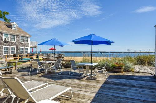 a deck with tables and chairs and blue umbrellas at Community beach and sundeck in Provincetown
