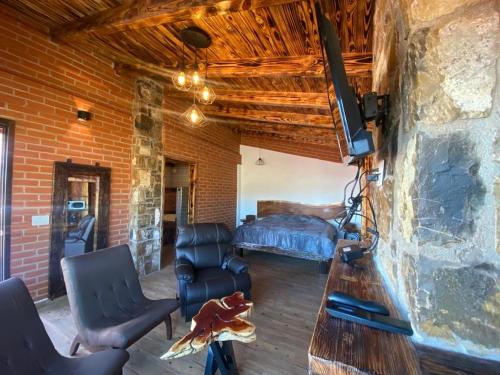 a living room with a bed and a tv in a brick wall at Cabañas Quinta Áthas in Huasca de Ocampo