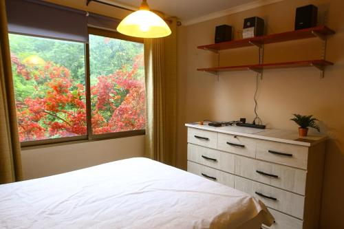 Un dormitorio con una cama y una cómoda y una ventana. en 3-room apartment steps from Los Dominicos, en Santiago