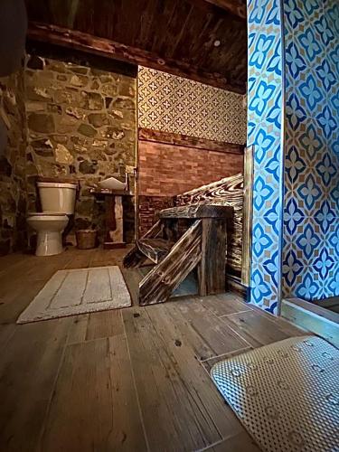 a bathroom with a toilet and a stone wall at Cabañas Quinta Áthas in Huasca de Ocampo