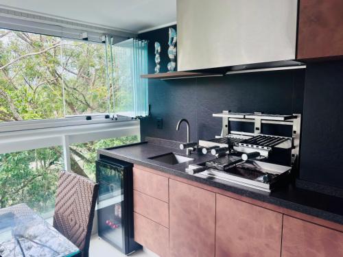 eine Küche mit Spüle und Theke mit Fenster in der Unterkunft Paraíso na Riviera São Lourenço - Laguna Home Resort in Riviera de São Lourenço