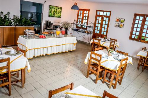 Un restaurante con mesas y sillas y una cocina. en Hotel Villa Real, en Crato