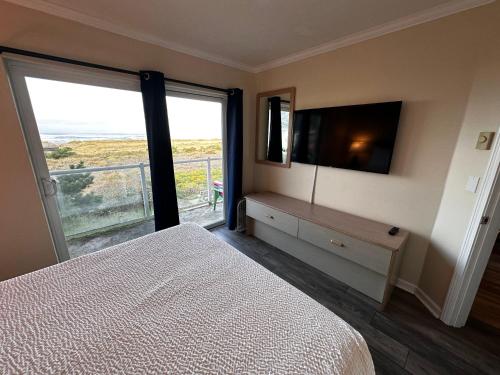 a bedroom with a bed and a television and a balcony at Inn at the Shore in Seaside