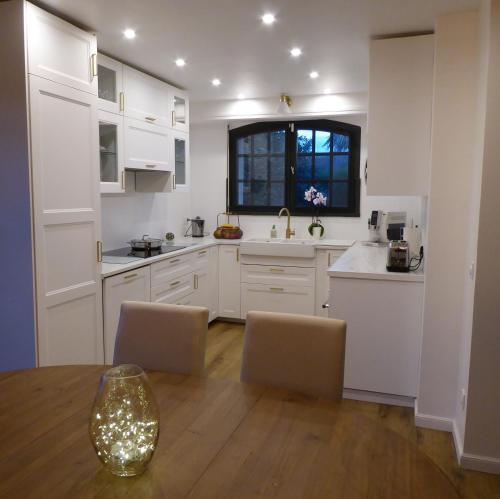 a kitchen with white cabinets and a table and chairs at Villa Gustavine - Maison d'Architecte in Ger