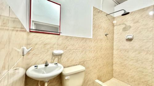 a bathroom with a sink and a toilet and a mirror at Hostal Maravilla Amazónica in Iquitos