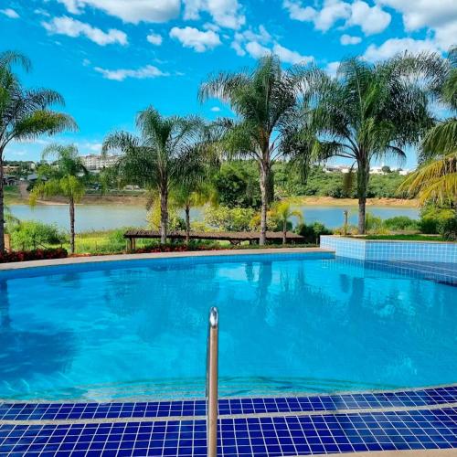 a swimming pool with a view of a river and palm trees at Ilhas do Lago Eco Resort in Caldas Novas