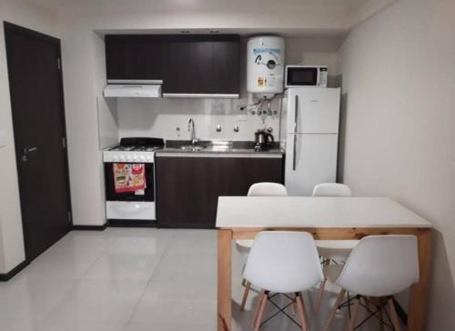 a small kitchen with a table and white appliances at Departamento en Alquiler en Carlos Paz in La Porteña